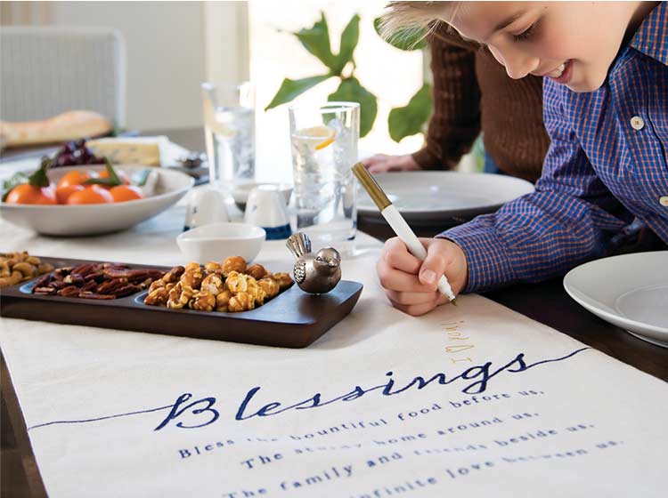 Boy writing a message on a customizable blessings table runner