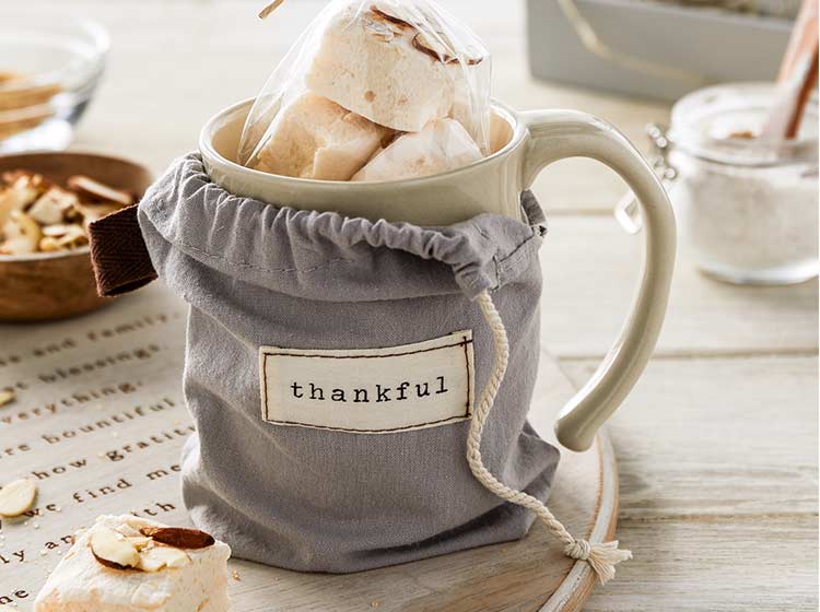 Mug full of snacks in a cloth bag with the word thankful sewn on